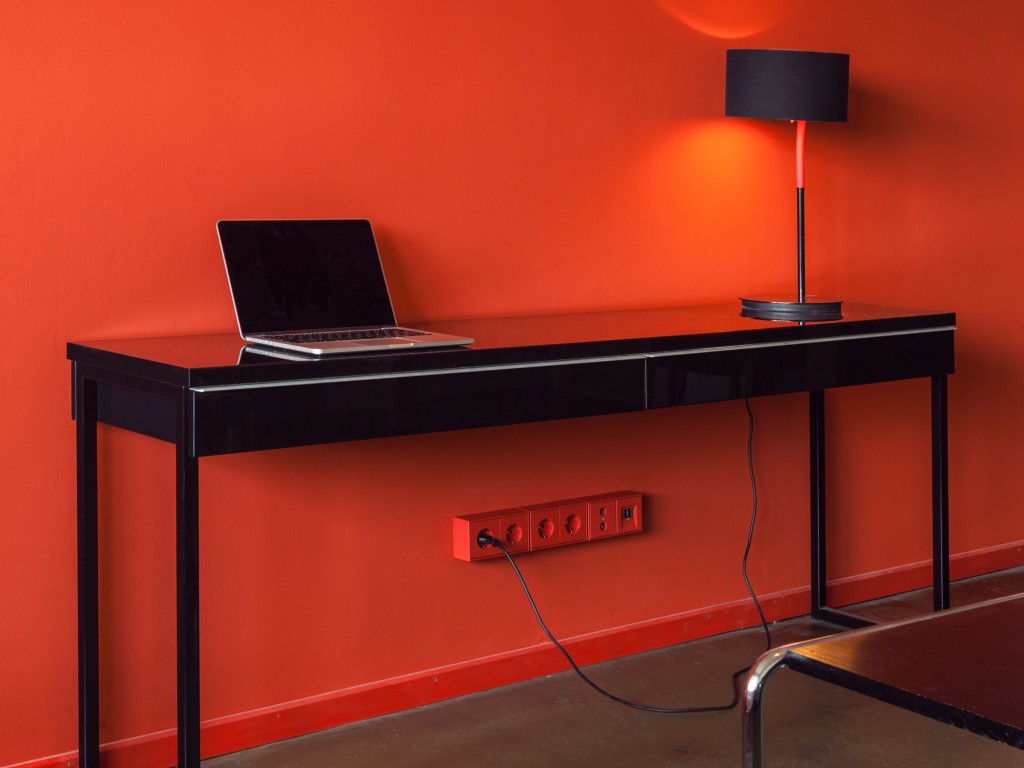Les Couleurs® Le Corbusier, gniazdka, czerwone gniazdka, czerwona ściana, biurko, laptop, lampka, projektowanie wnętrz